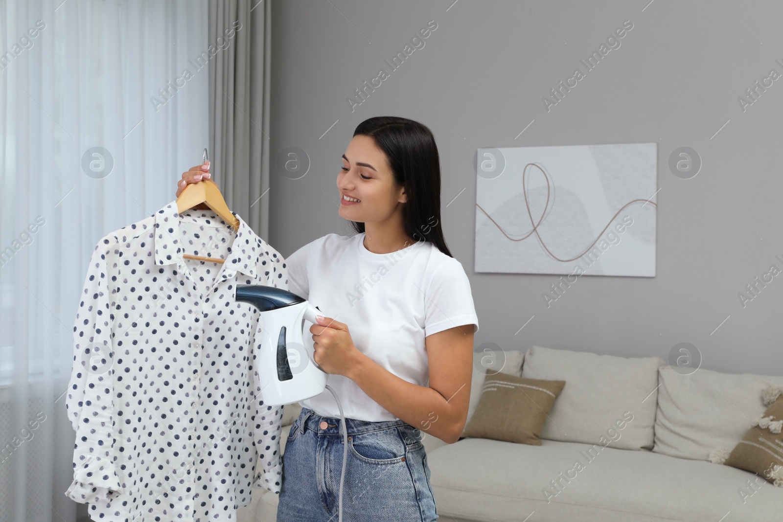 Photo of Woman steaming blouse on hanger at home. Space for text