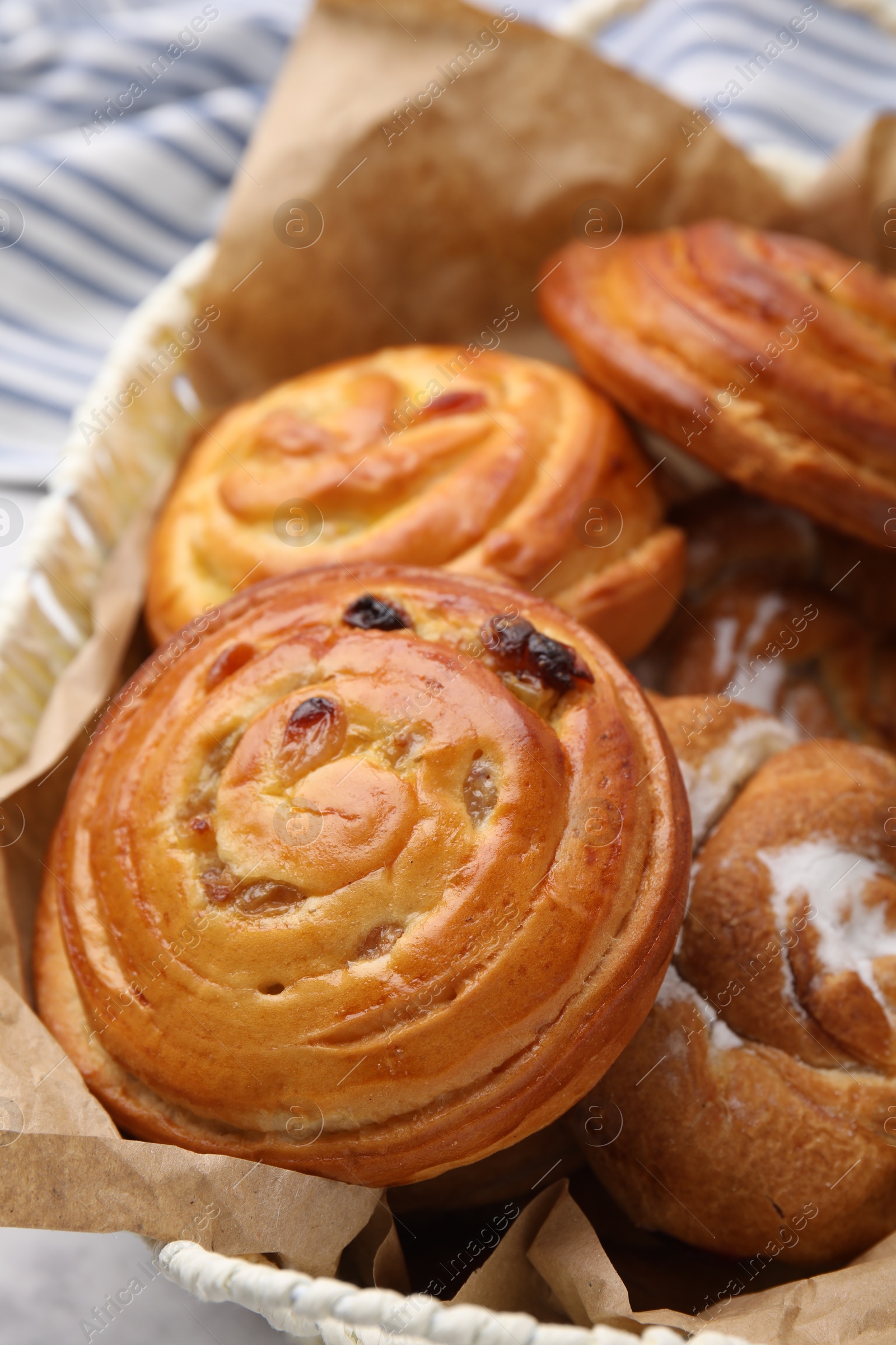 Photo of Delicious rolls with raisins and sugar powder on table, closeup. Sweet buns