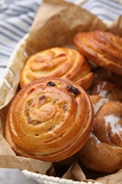 Photo of Delicious rolls with raisins and sugar powder on table, closeup. Sweet buns
