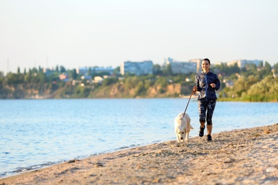 Photo of Young woman with her dog together on beach. Pet care