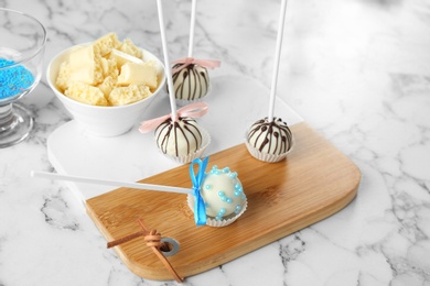 Tasty colorful cake pops on white marble table