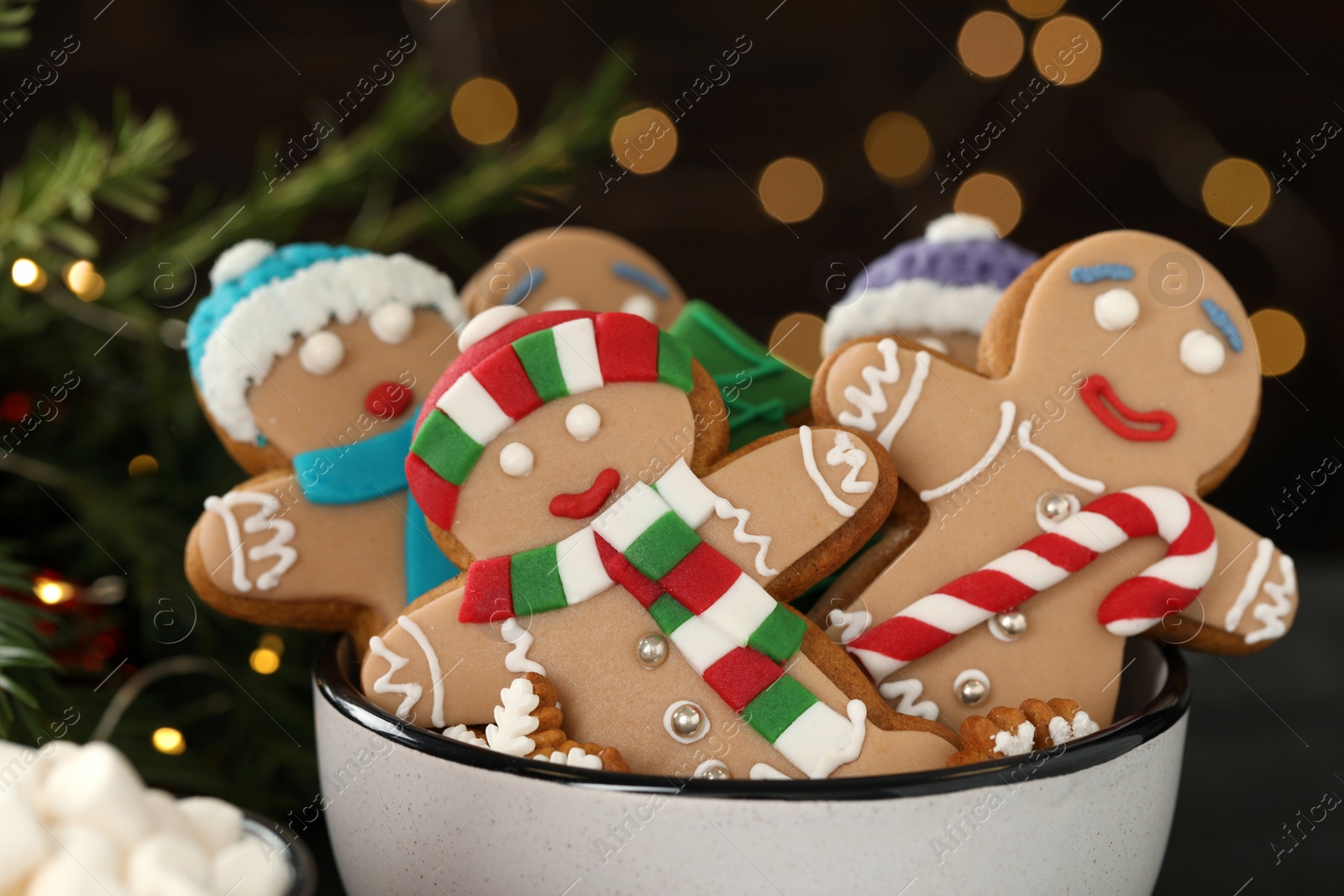 Photo of Delicious homemade Christmas cookies in bowl against blurred festive lights, closeup