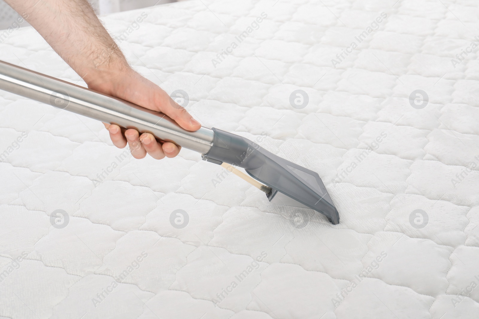 Photo of Man disinfecting mattress with vacuum cleaner, closeup. Space for text