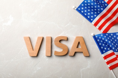 Photo of Flat lay composition with word VISA and flags of USA on gray background