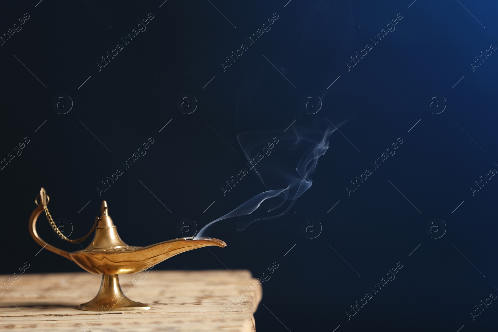 Photo of Aladdin lamp of wishes on wooden table against dark background