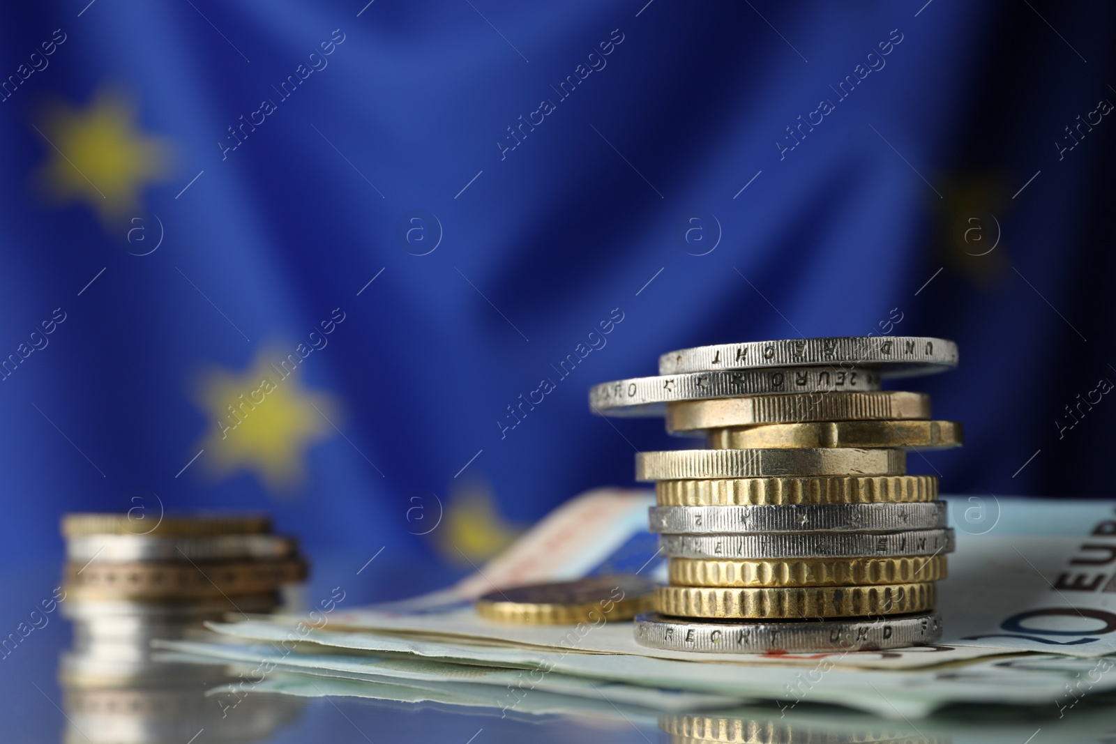 Photo of Coins and banknotes on table against European Union flag, closeup. Space for text