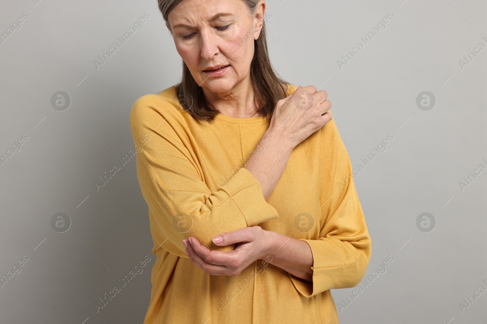 Photo of Arthritis symptoms. Woman suffering from pain in elbow on gray background