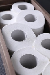 Photo of Many toilet paper rolls in wooden crate on table