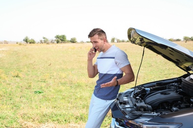 Man talking on phone near broken car outdoors. Space for text