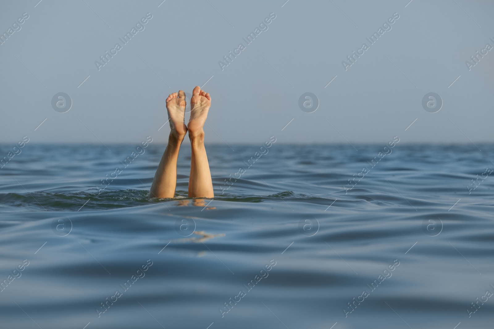 Photo of Drowning woman's legs sticking out of sea