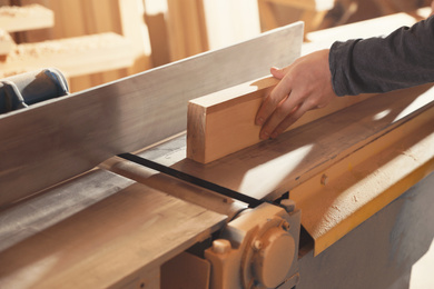 Professional carpenter working with surface planer in workshop, closeup