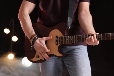 Photo of Man playing electric guitar on stage, closeup. Rock concert
