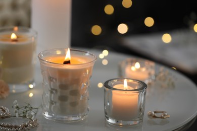 Burning candles and jewelry on table indoors