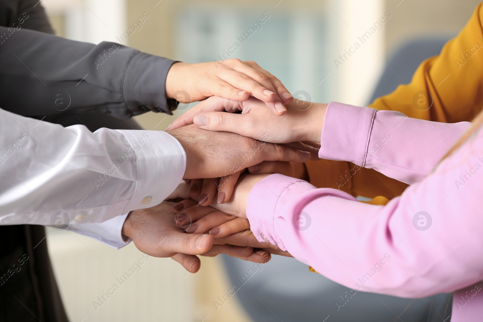 Photo of Young people putting their hands together on blurred background, closeup