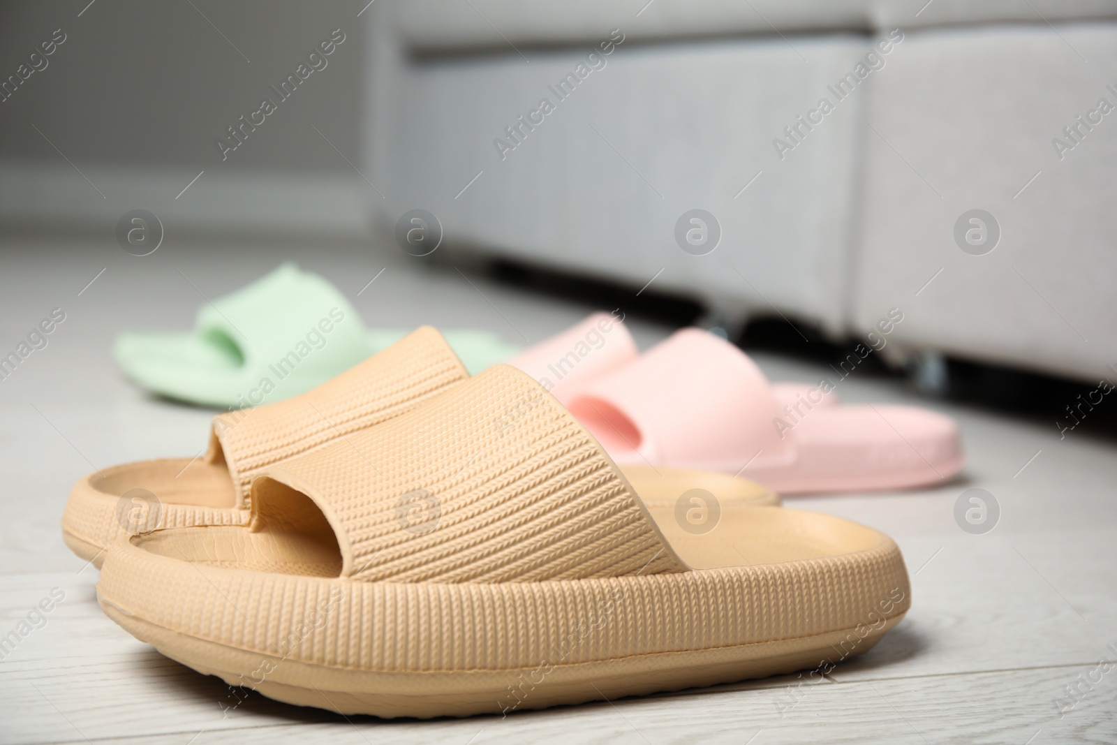 Photo of Stylish rubber slippers on floor in room, closeup