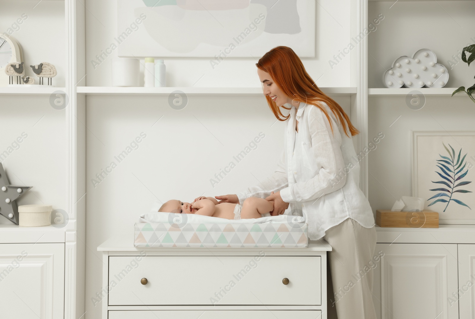 Photo of Mother with her baby at changing table indoors