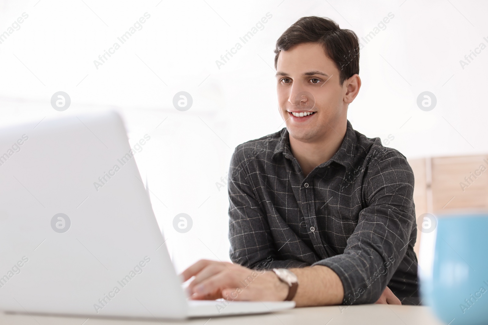 Photo of Portrait of confident young man with  laptop at table