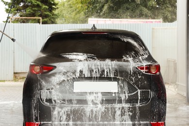 Washing auto with high pressure water jet at outdoor car wash