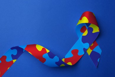Image of World Autism Awareness Day. Colorful puzzle ribbon on blue background, top view