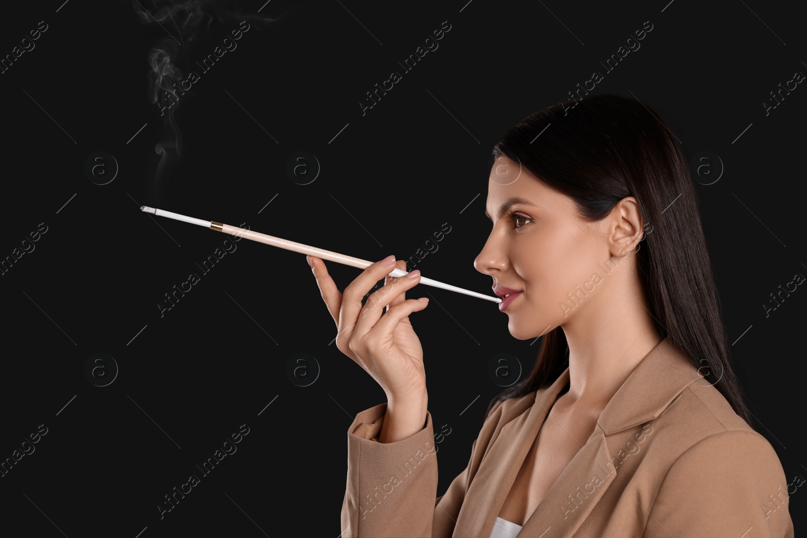 Photo of Woman using long cigarette holder for smoking on black background