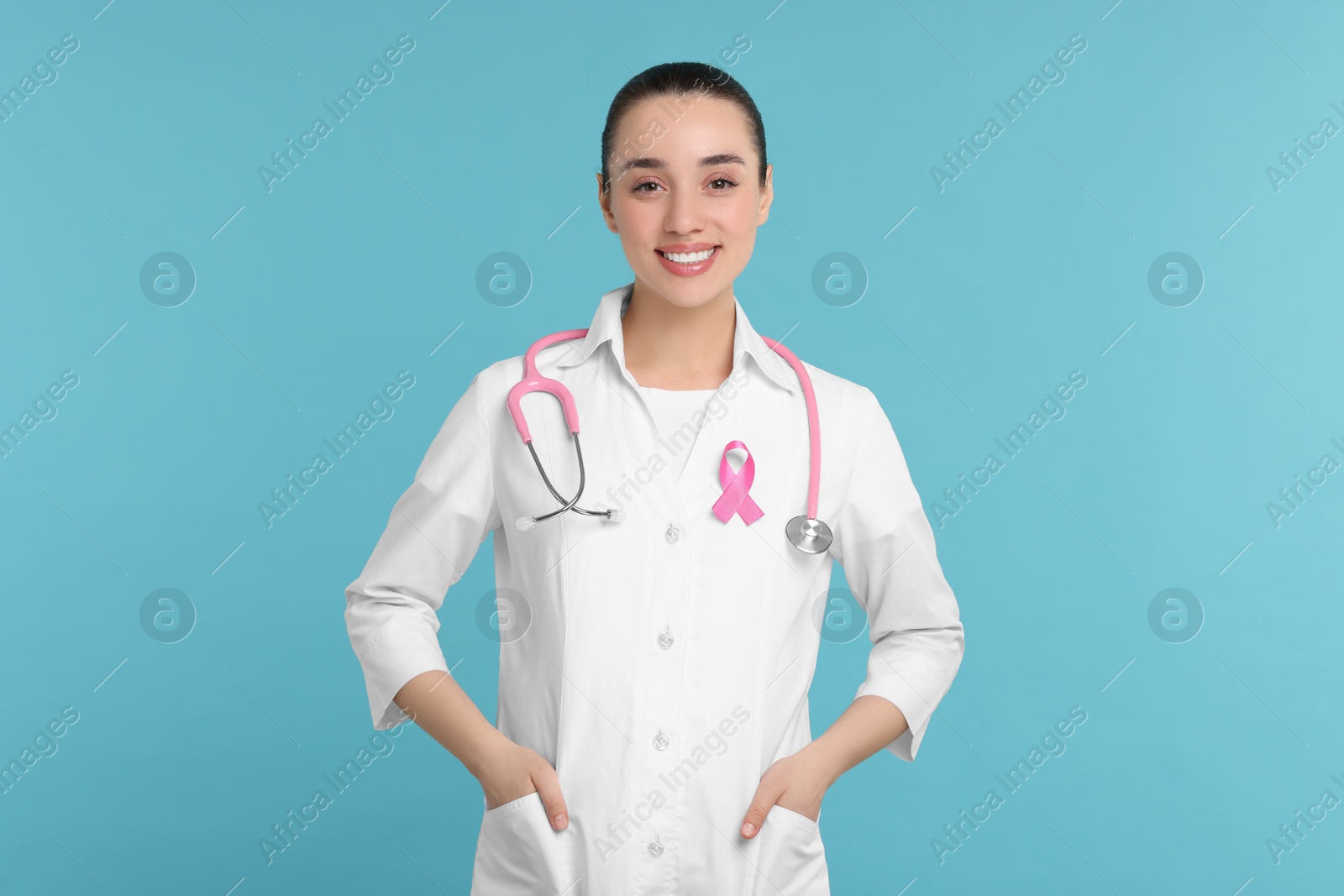 Photo of Mammologist with pink ribbon on light blue background. Breast cancer awareness