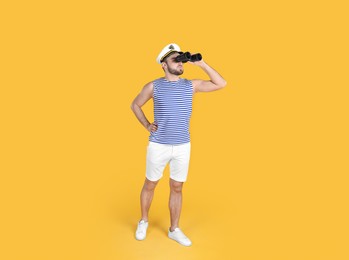 Photo of Young sailor with binoculars on yellow background