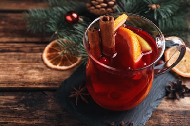 Photo of Tasty aromatic mulled wine on wooden table, closeup
