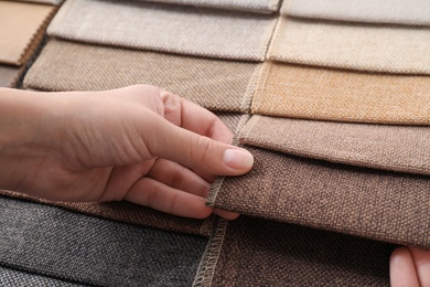 Photo of Young woman choosing among upholstery fabric samples, closeup. Interior design