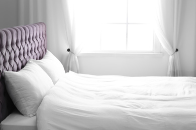 Photo of Modern bed with soft pillows near window