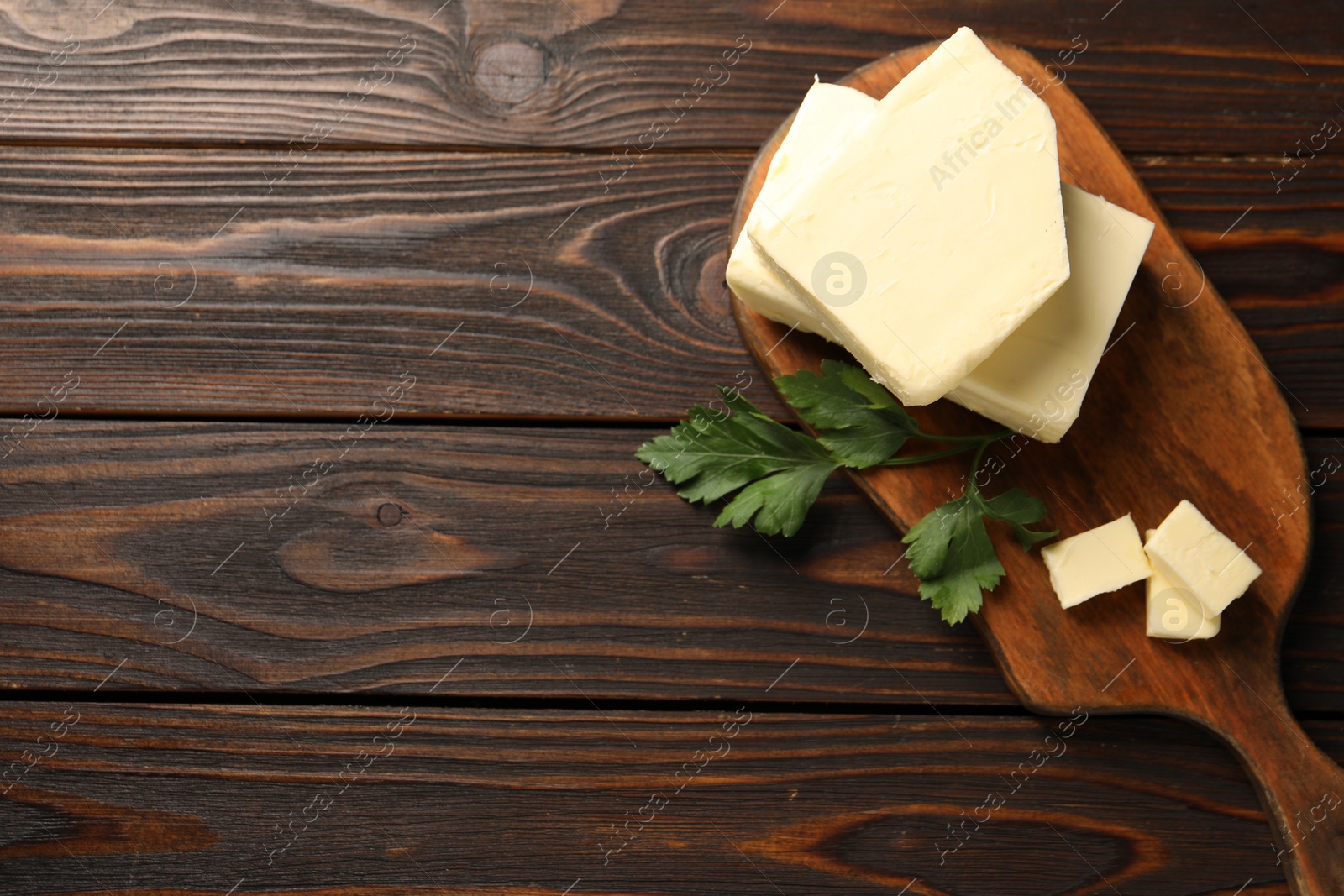 Photo of Tasty butter and parsley on wooden table, top view. Space for text