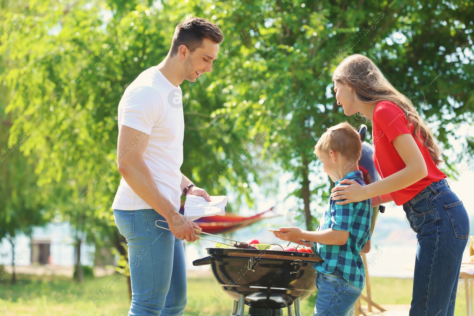 Photo of Happy family having barbecue with modern grill outdoors