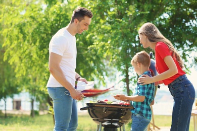 Photo of Happy family having barbecue with modern grill outdoors