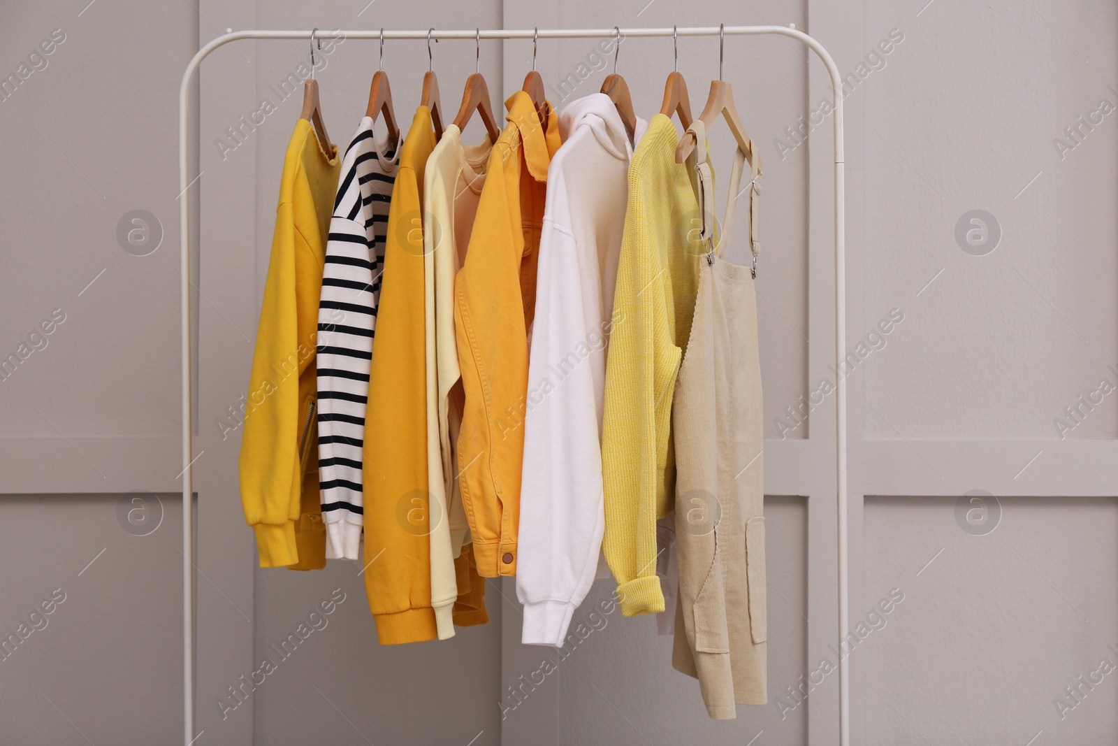 Photo of Rack with stylish women's clothes near light wall