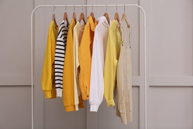 Photo of Rack with stylish women's clothes near light wall