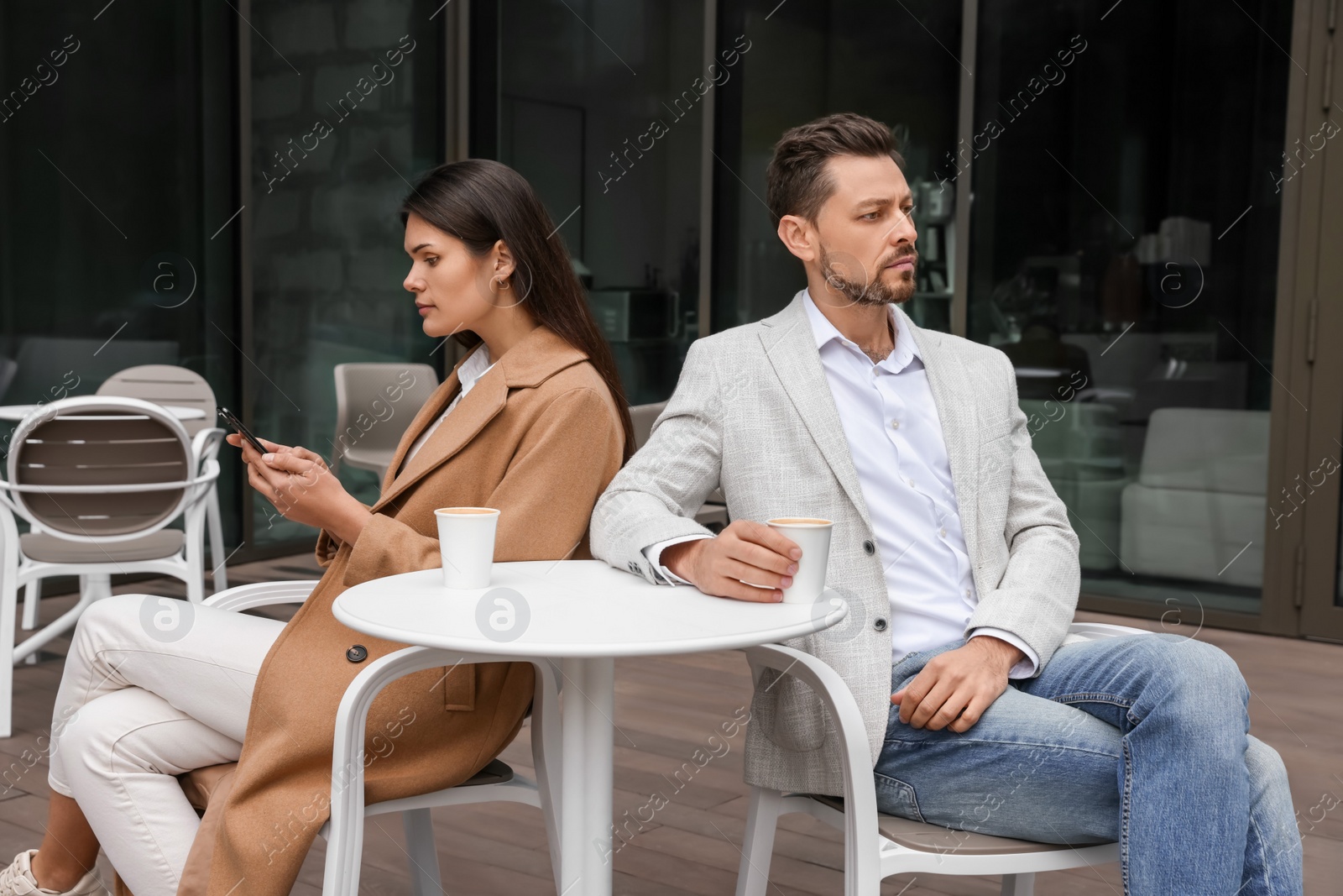 Photo of Upset arguing couple in outdoor cafe. Relationship problems