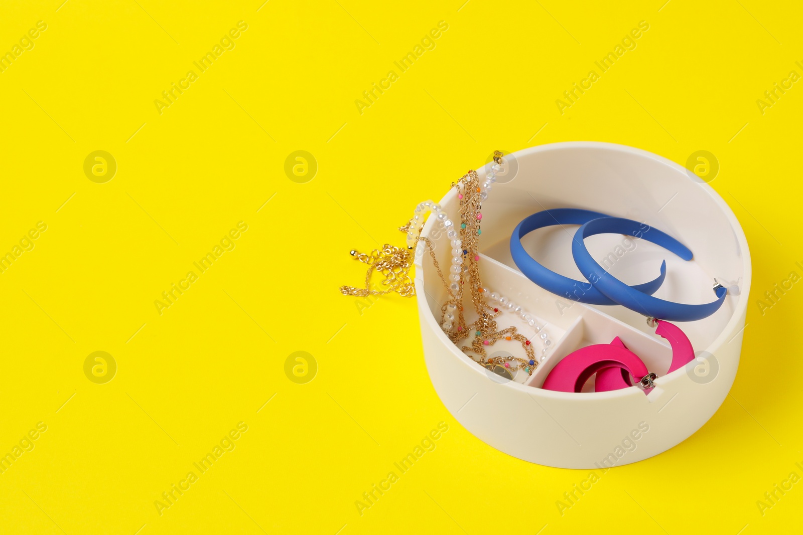 Photo of Jewelry box with many different accessories on yellow background, space for text