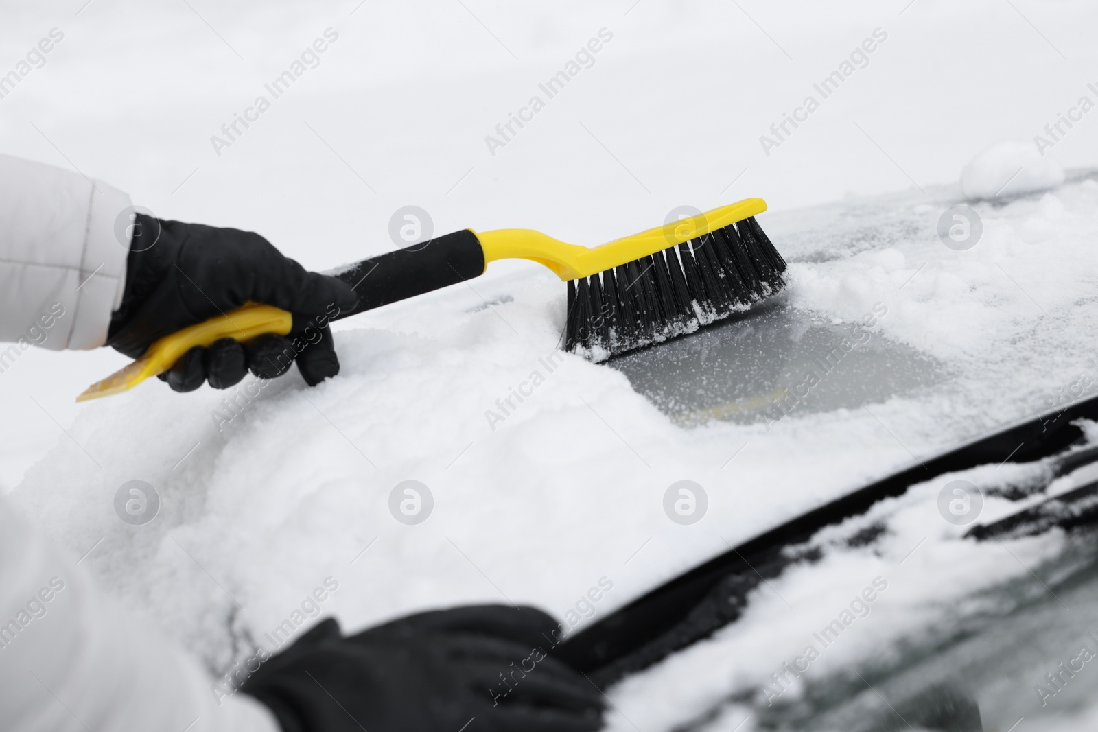 Photo of Man cleaning snow from car hood outdoors, closeup