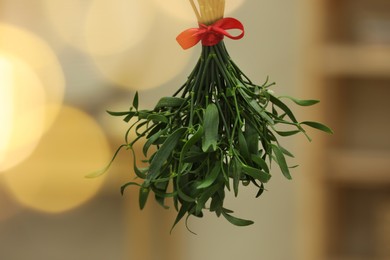Photo of Mistletoe bunch with red bow on blurred background. Traditional Christmas decor