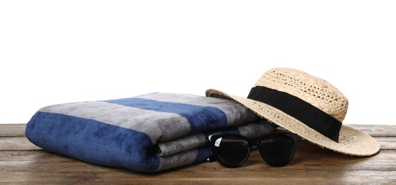 Beach towel, straw hat and sunglasses on wooden surface against white background