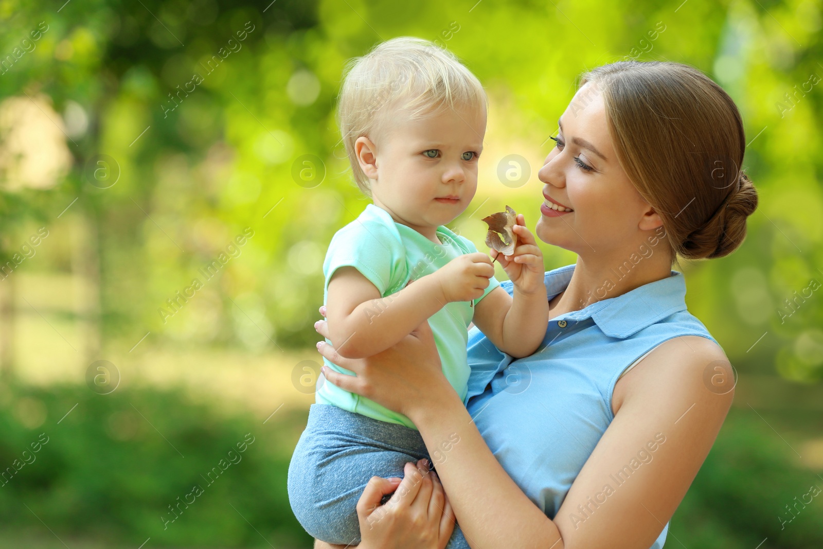 Photo of Young mother with her cute child in green park