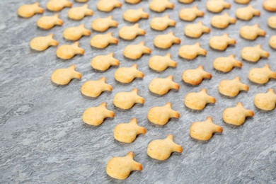 Photo of Delicious goldfish crackers on grey table, closeup