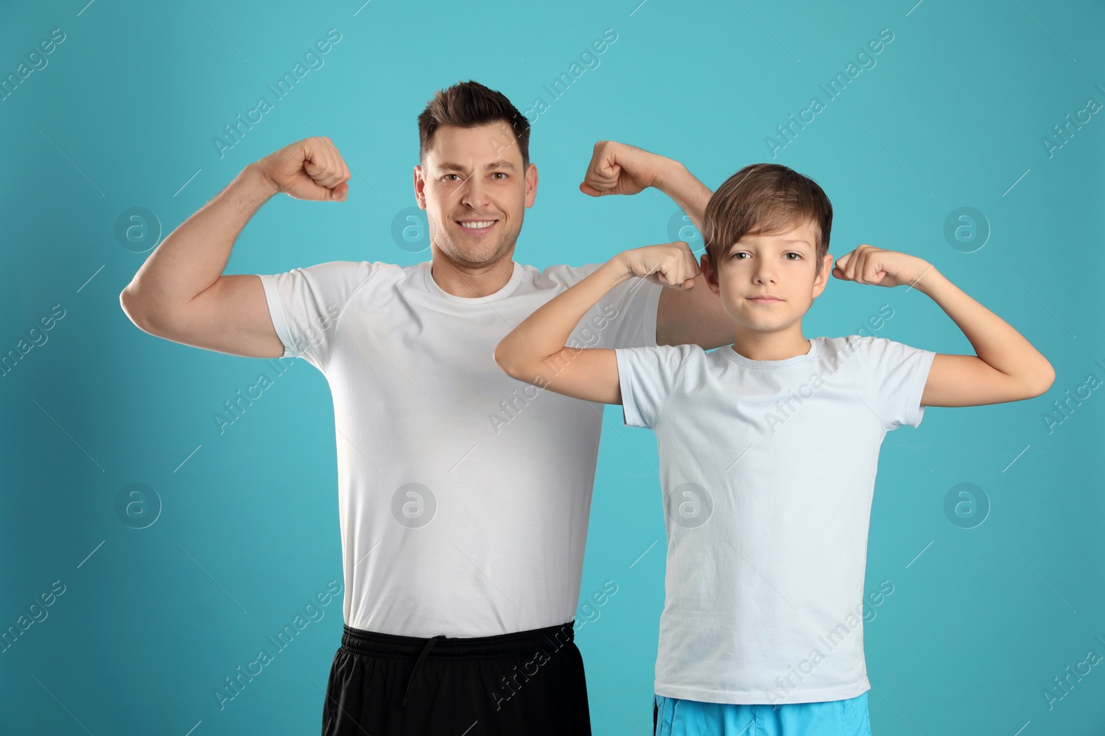 Photo of Portrait of sporty dad and his son on color background