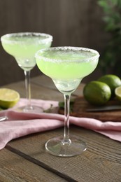 Delicious Margarita cocktail in glasses on wooden table, closeup