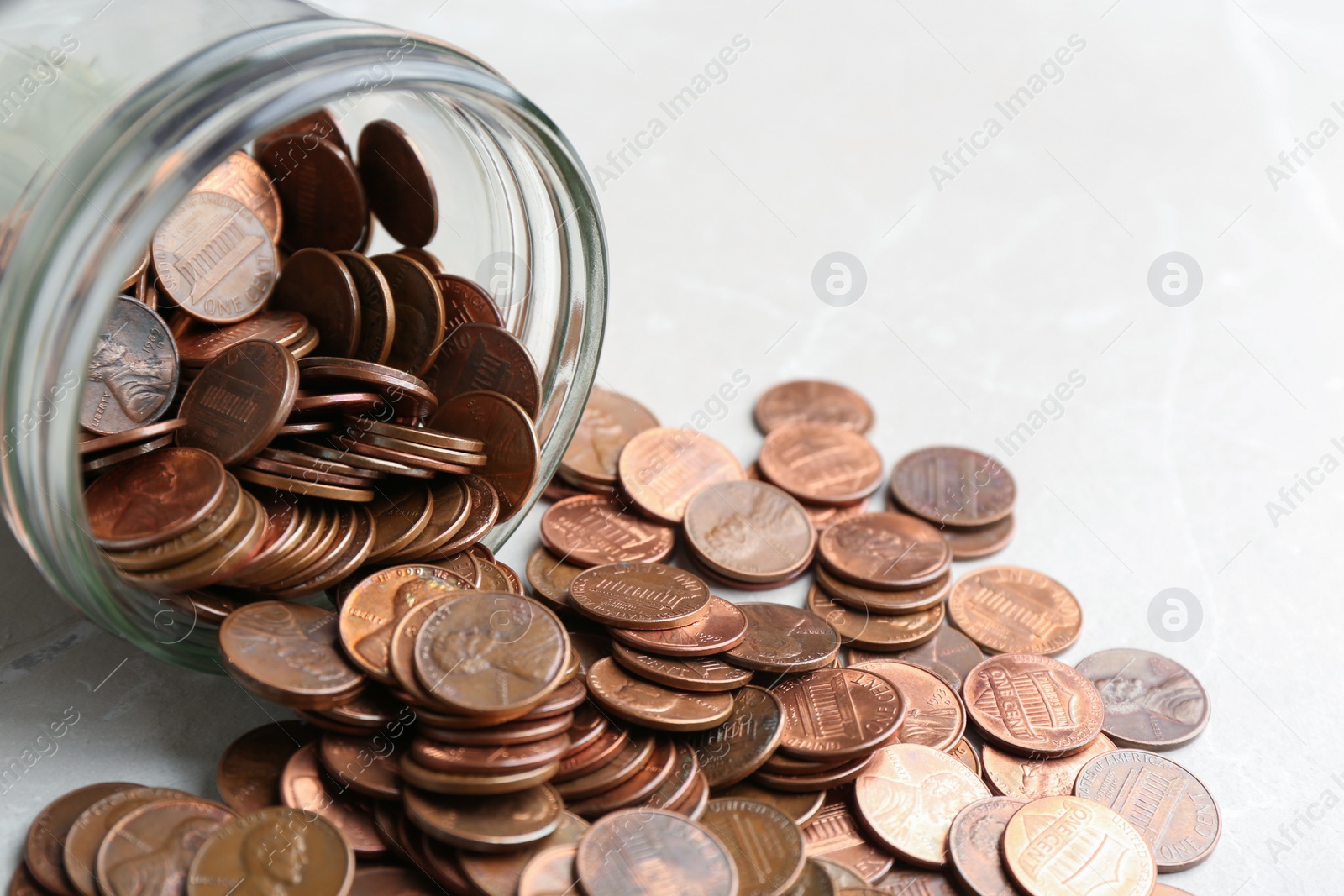 Photo of Overturned glass jar with coins on table, closeup