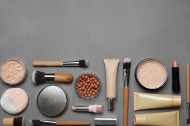 Photo of Face powders and other makeup products on grey background, flat lay. Space for text