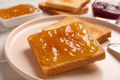 Toast with tasty orange jam and roasted slice of bread on plate, closeup