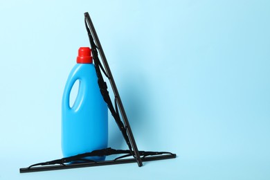 Photo of Bottle of windshield washer fluid and wipers on light blue background. Space for text