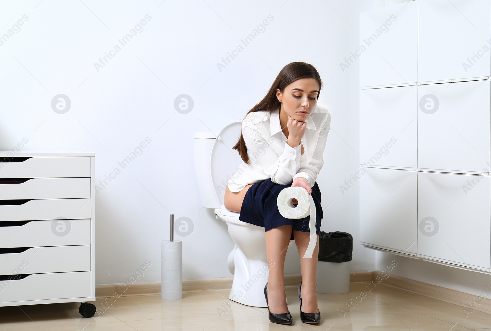 Photo of Upset woman sitting on toilet bowl in bathroom