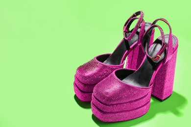 Fashionable punk square toe ankle strap pumps on green background, space for text. Shiny party platform high heeled shoes