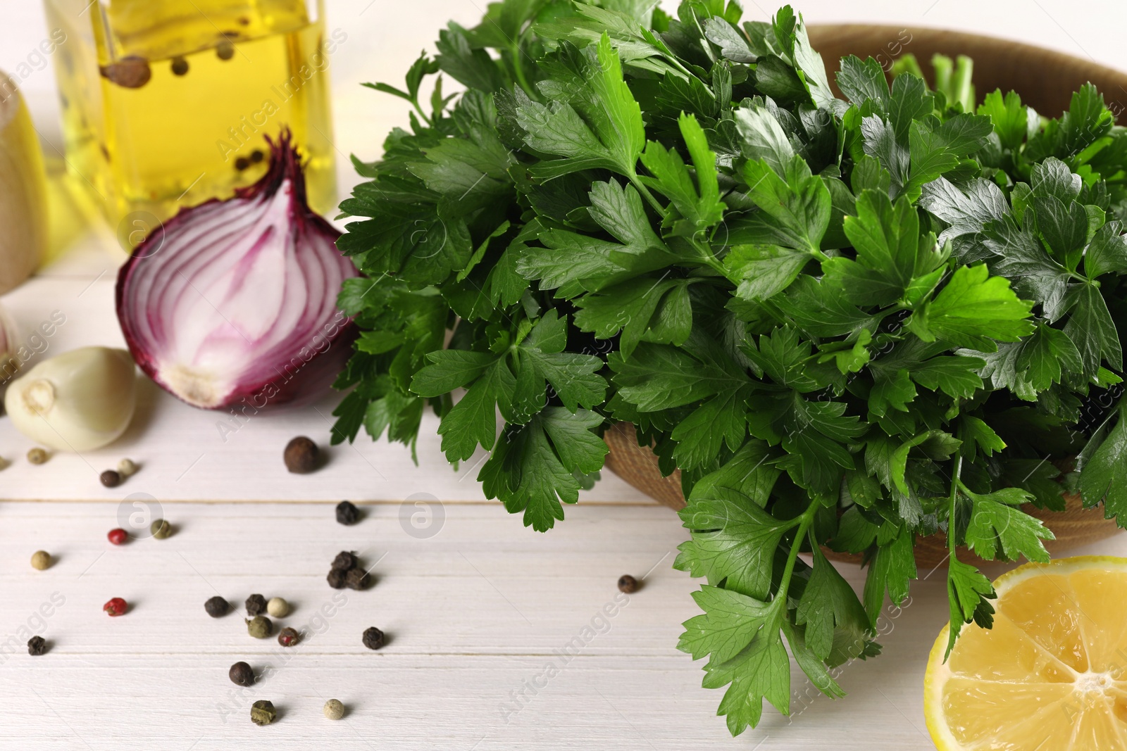 Photo of Fresh green parsley, spices and other products on white wooden table